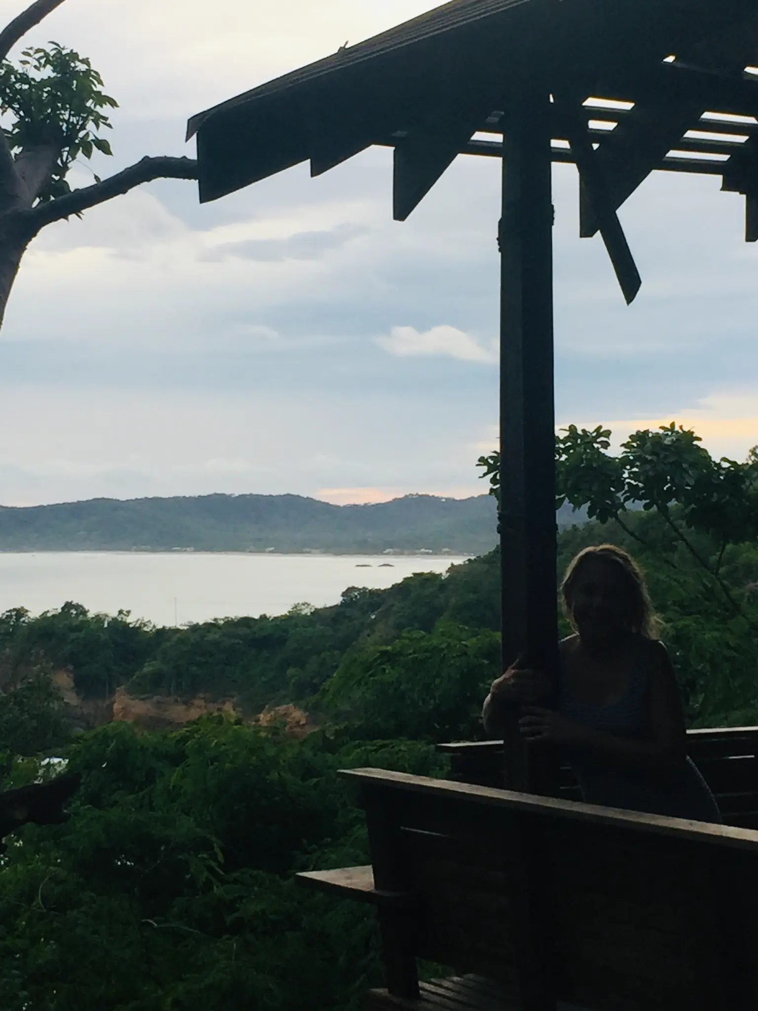 Sitting under a pergola at Aqua Resort with sweeping views of the Pacific bay and jungle hills at dusk