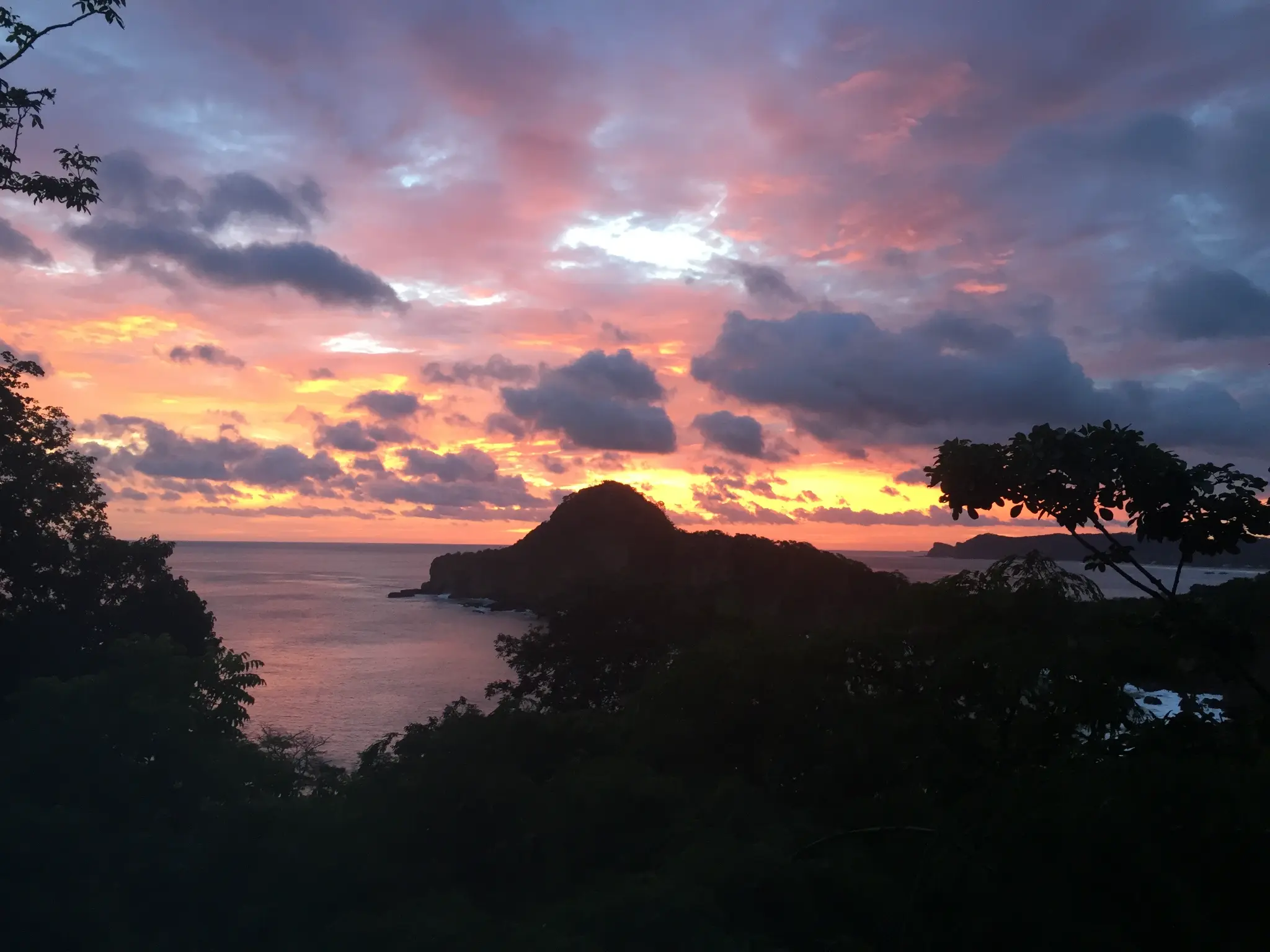 Pacific sunset from Aqua Resort Nicaragua — fiery orange and pink sky over the Emerald Coast headland