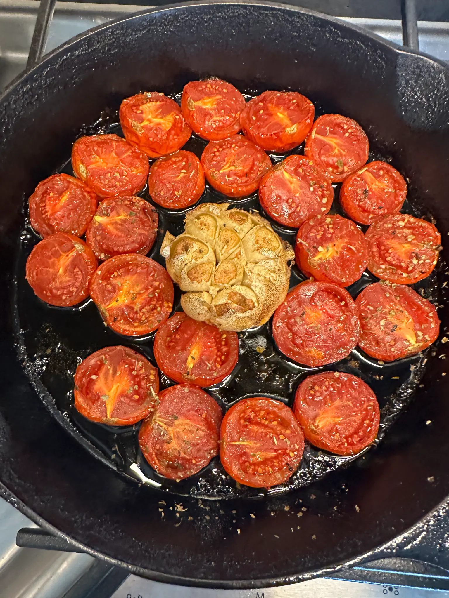 Roasted Campari tomatoes and whole roasted garlic head in a cast iron skillet fresh from the oven