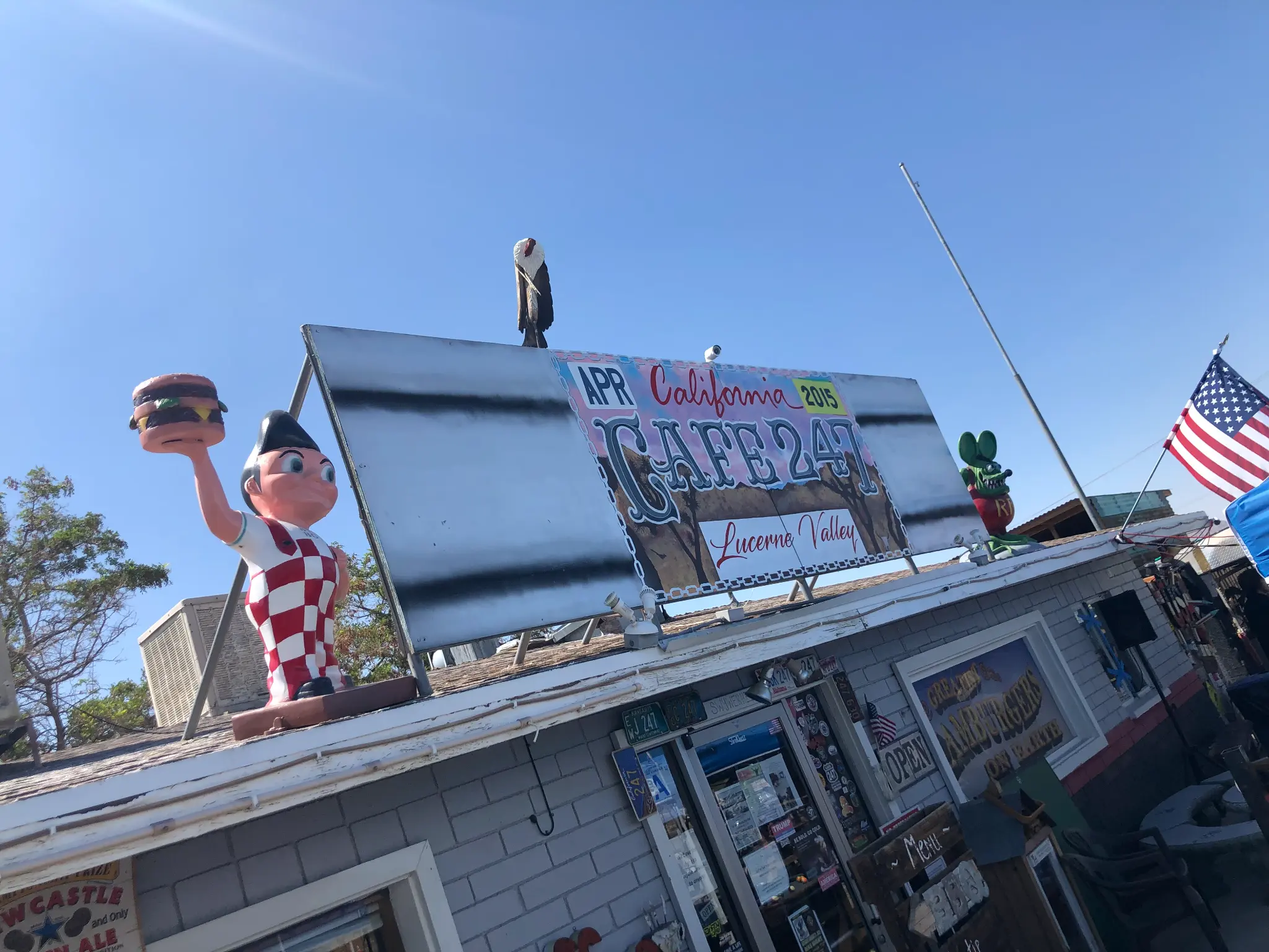 Cafe 247 in Lucerne Valley β Bob's Big Boy statue on the roof holding a burger, colorful signage against a blue sky
