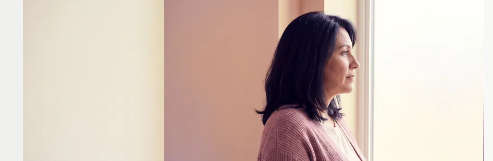 Woman standing at a window in quiet reflection