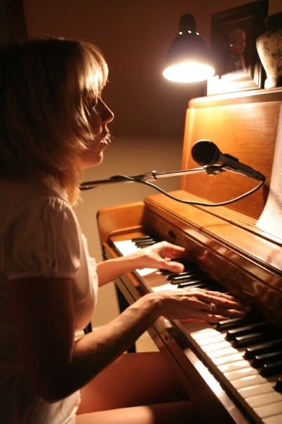 Kristen playing piano under a warm lamp