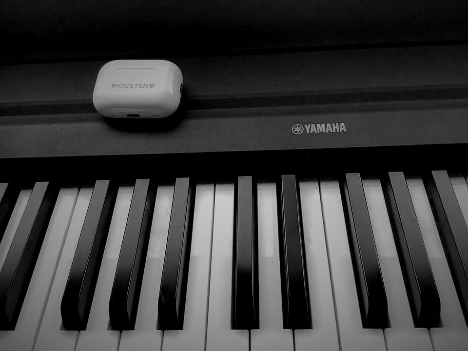 Kristen's Yamaha piano with custom AirPods case engraved with her name