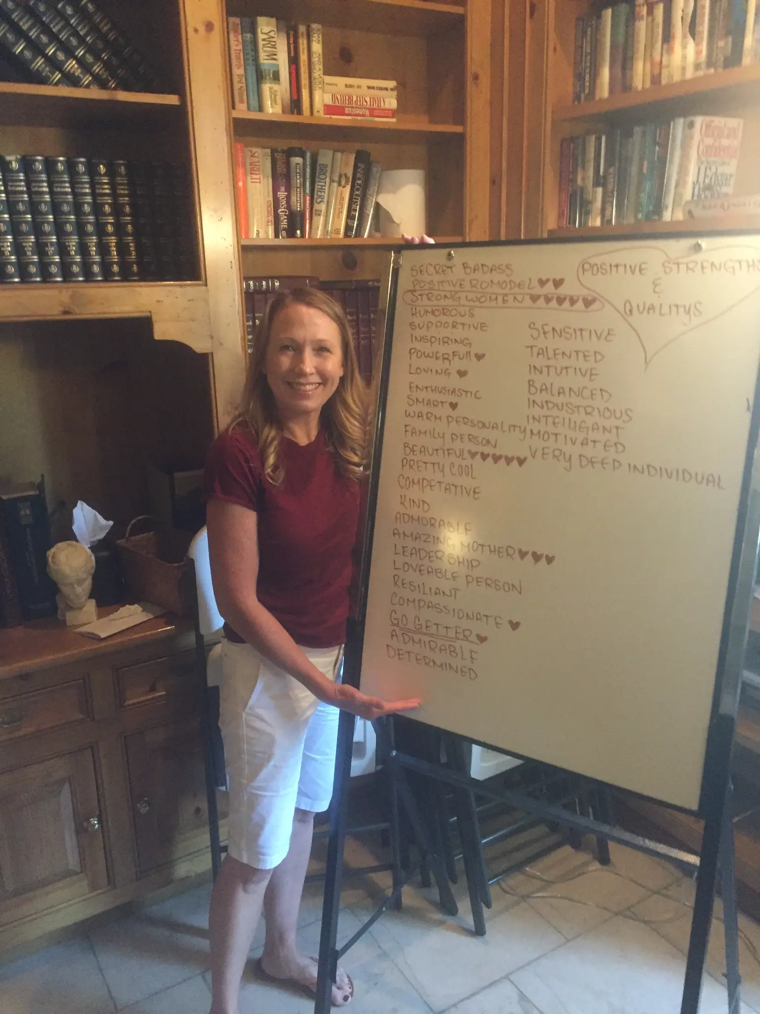 Kristen standing next to the whiteboard filled with positive qualities written by her fellow patients at Harmony Place