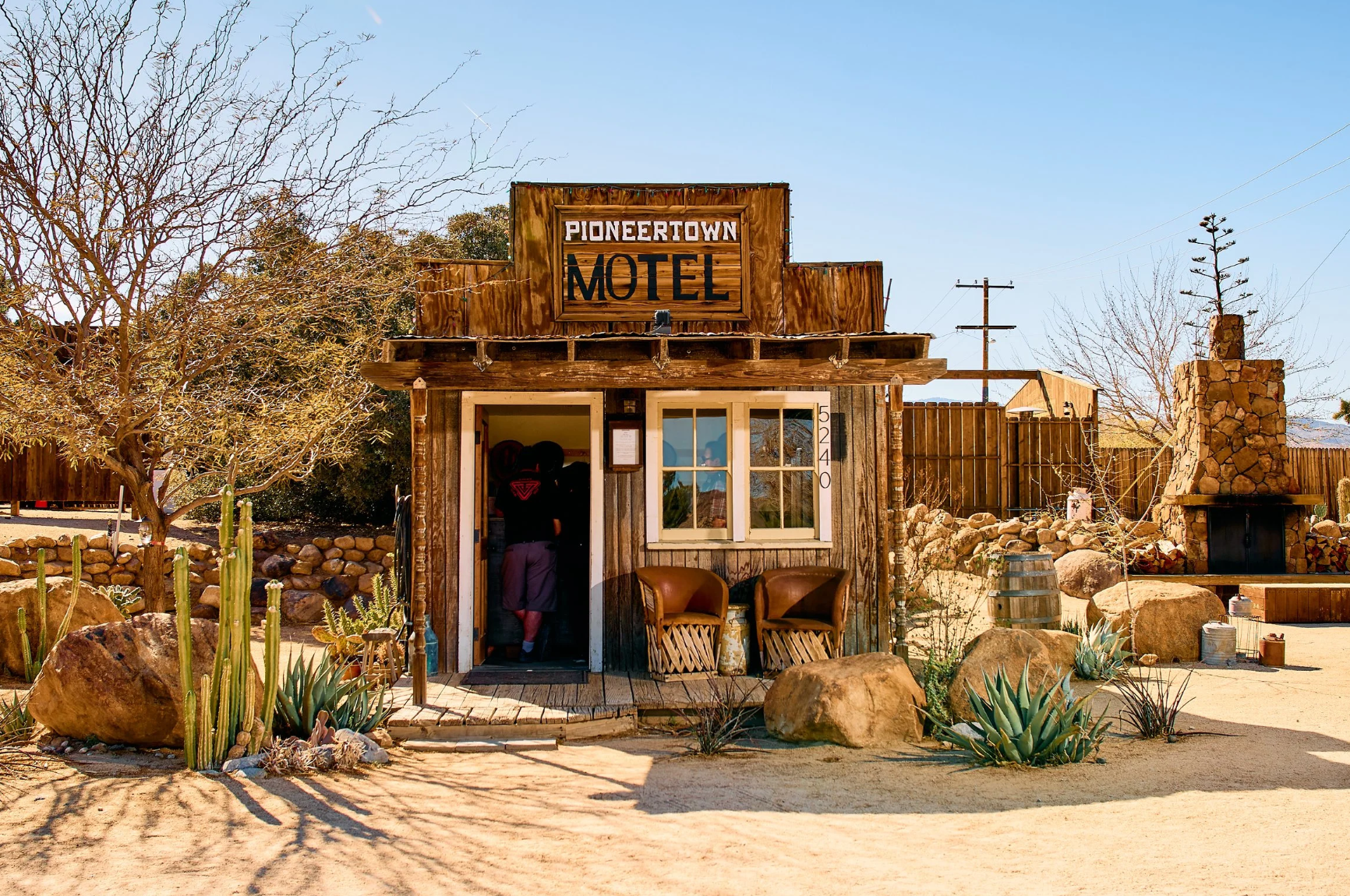 The Pioneertown Motel β a rustic Old West-style building with cactus and desert boulders out front